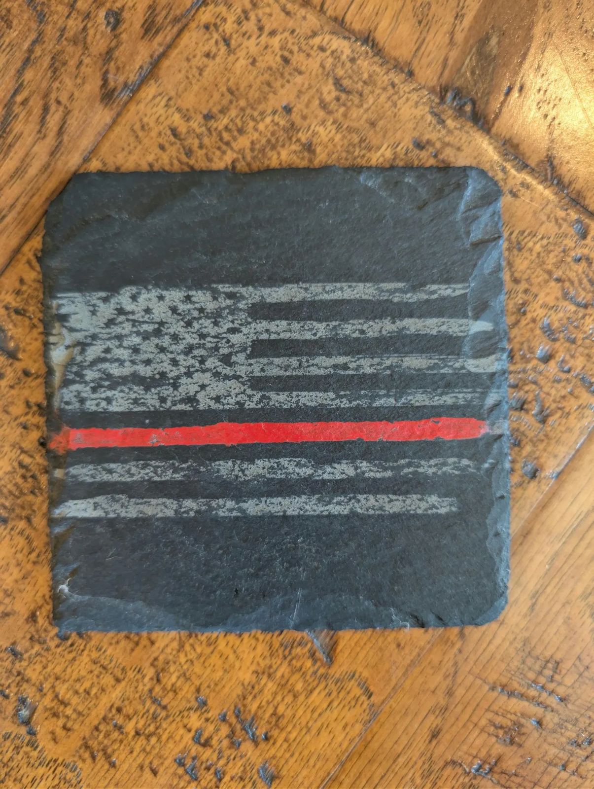 Black slate coaster engraved with a distressed American flag and red line
