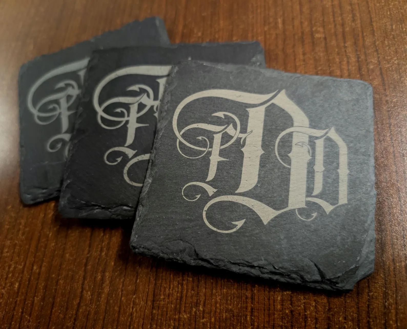 Set of personalized natural slate coasters engraved with an ornate monogram